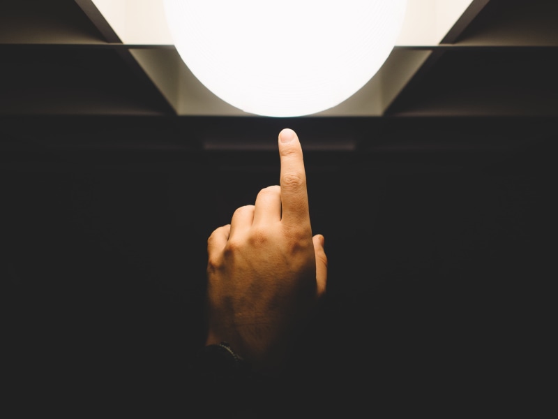 lighting equipment, one person, human body part, gesturing, communication, people, indoors, body part, lamp, technology, focus, finger, unrecognizable person