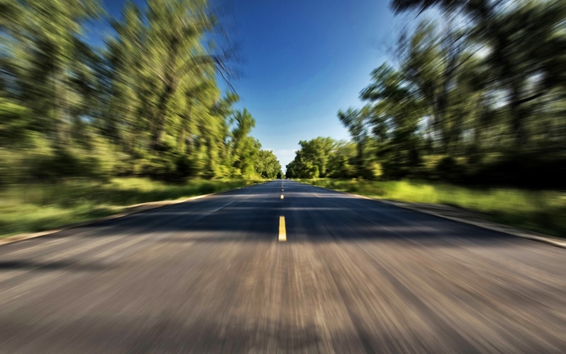 road marking, symbol, no people, plant, highway, outdoors, diminishing perspective, motion, blurred motion, trees, motion blur, rural scene, direction