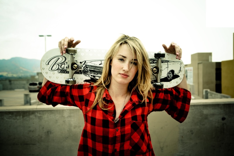 black, real people, focus on foreground, emotion, casual clothing, one person, waist up, young women, hairstyle, skateboard, day, Ashley Johnson, cruiser