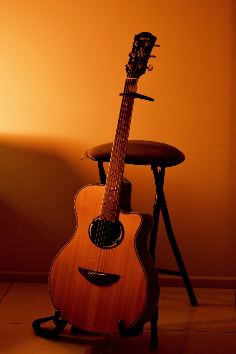 indoors, wall - building feature, electric guitar, silhouette, string instrument, string, hardwood floor, colored background, lute, musical equipment, orange background
