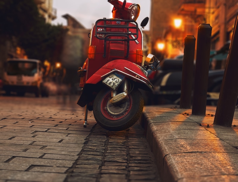 stationary, cobblestone, vehicle, road, vehicles, building exterior, blur, night, scooter, motor, sidewalk, motor vehicle, city, mode of transportation