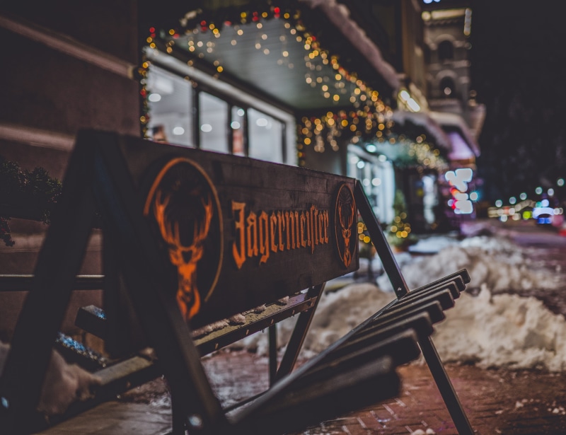 rail transportation, jagermeister, dark, photo, railroad track, lights, winter, western script, 5K, metropolis, selective, illuminated, night, forge, building
