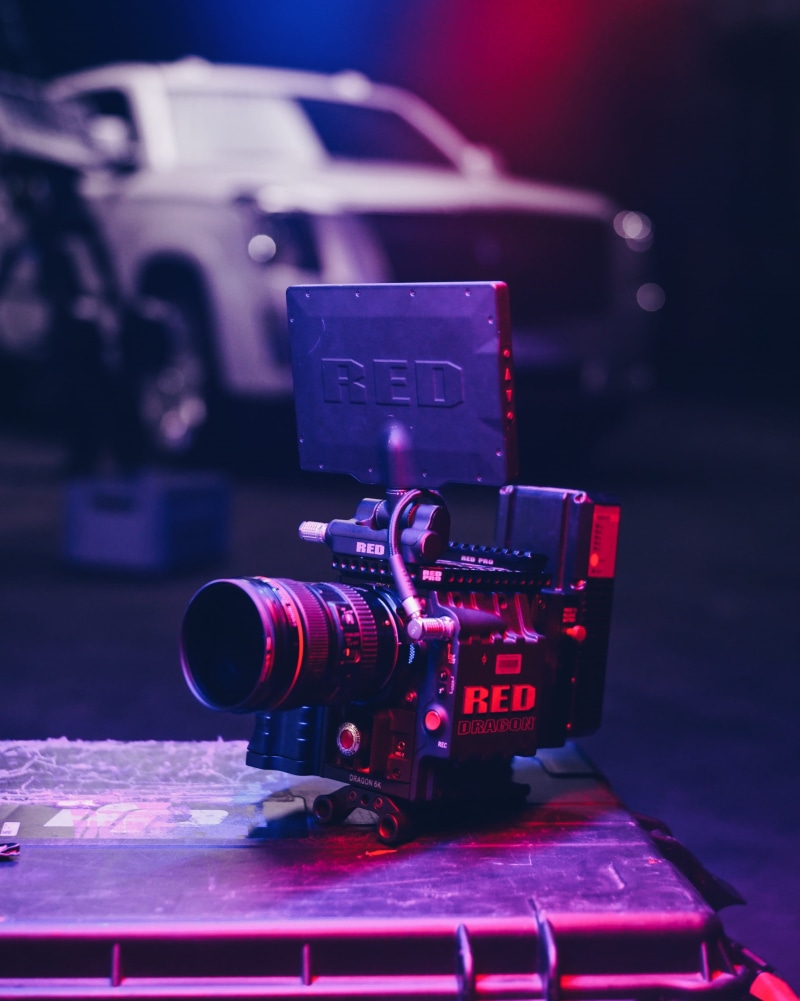redcamera, still life, film reel, red, lighting, cinematographer, focus on foreground, photo, car, video camera, equipment, no people, photographic equipment