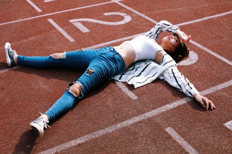 sports clothing, tired, healthy lifestyle, torn jeans, women, running track, white tops, Converse, competition, lying down, track and field athlete, young adult