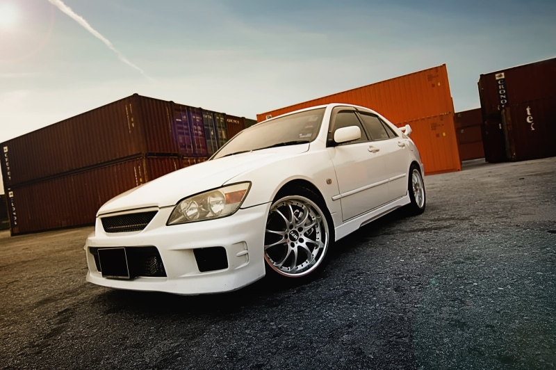 built structure, business, shiny, land Vehicle, metal, sedan, tire, industry, car, cargo Container, no People, fleet of Vehicles, luxury, street, front View