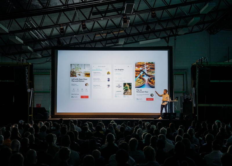 presenting, male, room, crowd, indoors, speaker, screen, man, stage, arts culture and entertainment, projection screen, people, standing, lighted, adult