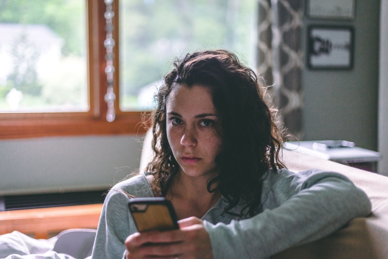 brown hair, mobile phone, person, lifestyles, indoors, wireless technology, serious, curly hair, phone, couch potato, holding, portable information device