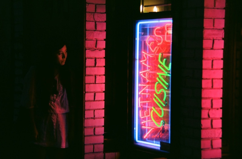 portrait, standing, neon sign, shadow, western script, outdoors, looking, wall - building feature, signage, built structure, mid adult, one person, colorful