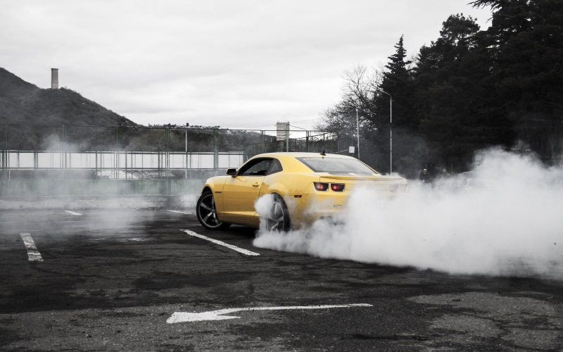 street, smoke - physical structure, no people, coupe, tree, transportation, vehicle, motion, land vehicle, smoke, yellow, city, outdoors, plant, architecture