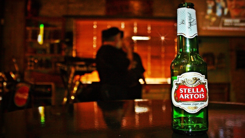 Stella Artois, refreshment, beer, happy hour, food and drink, indoors, drink, container, beer - alcohol, bar counter, western script, glass - material