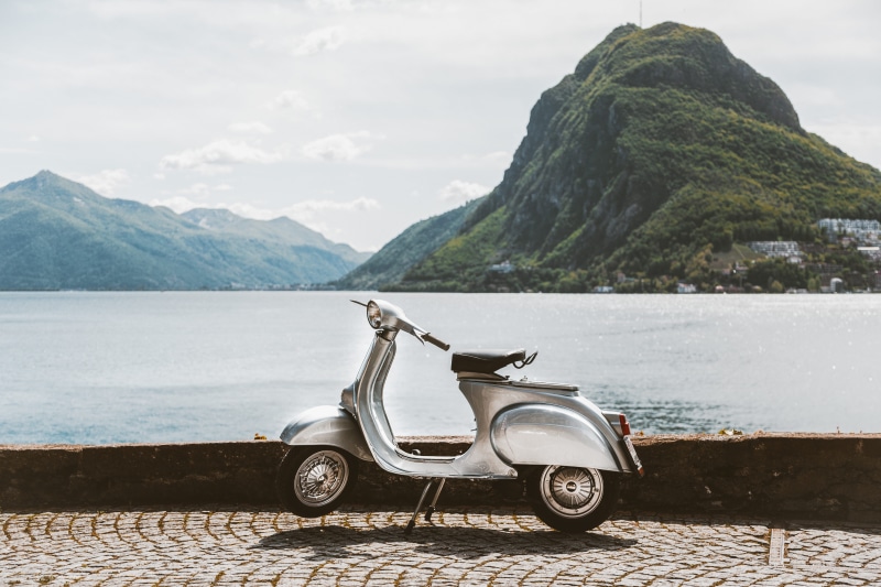 water, beauty in nature, stationary, vespa, bike, mountain, vintage, wheels, outdoors, mountains, parked, mode of transportation, near, non-urban scene