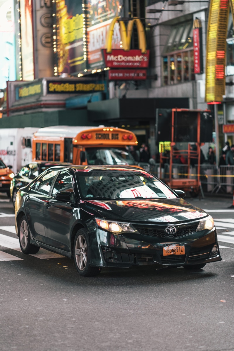 sports car, architecture, intersection, taxi, wheel, zebra crossing, building exterior, human, road, transportation, text, street, incidental people, sedan