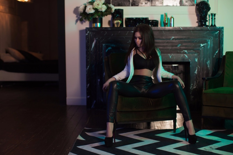 fireplace, white shirt, leather pants , leisure activity, sitting, hairstyle, skinny, long hair, casual clothing, relaxation, spread legs, one person, real people