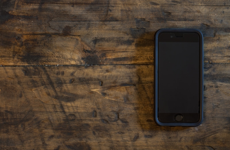 cell phone, table, wood grain, board, desk, indoors, smart phone, turned, brown, black color, directly above, no people, modern, screen, blank, cellphone
