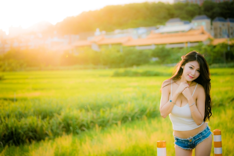 jean shorts, women, plant, tank top, three quarter length, standing, cleavage, smiling, adult, focus on foreground, hairstyle, brunette, lifestyles, field