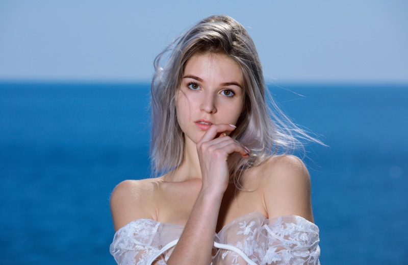 brown eyes, photo, bare shoulders, 5K, Libby, looking at camera, mouth, strapless, sea, finger on lips, lips, brunette, looking at viewer, dress, model