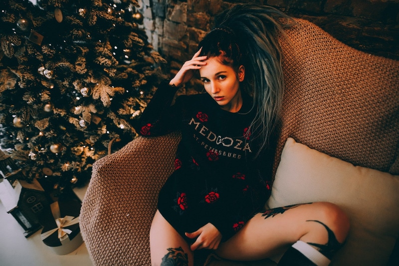 looking at viewer, contemplation, women indoors, real people, clothing, s, sweater, portrait, dyed hair, model, tattoo, pierced septum, beautiful woman