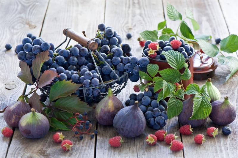 food, food and drink, container, table, fruit, grapes, blueberry, wellbeing, plant part, baskets, variation, leaf, purple, freshness, close-up, high angle view