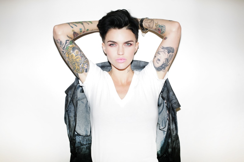 white background, looking at camera, beautiful woman, human arm, tattoo, ruby rose , short hair, one person, standing, studio shot, confidence, waist up