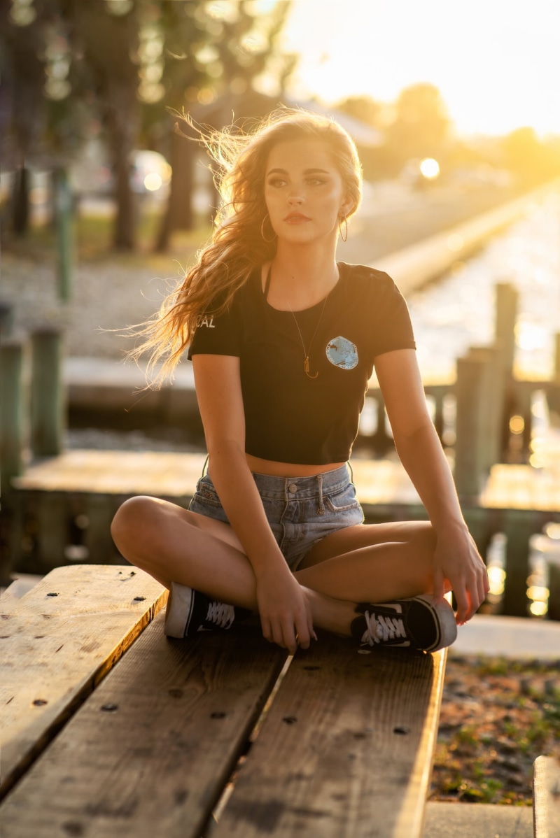 Christopher Rankin, necklace, hoop earrings, jean shorts, Alexis Rose, portrait display, T-shirt, model, women outdoors, sitting, 1080P, outdoors, depth of field
