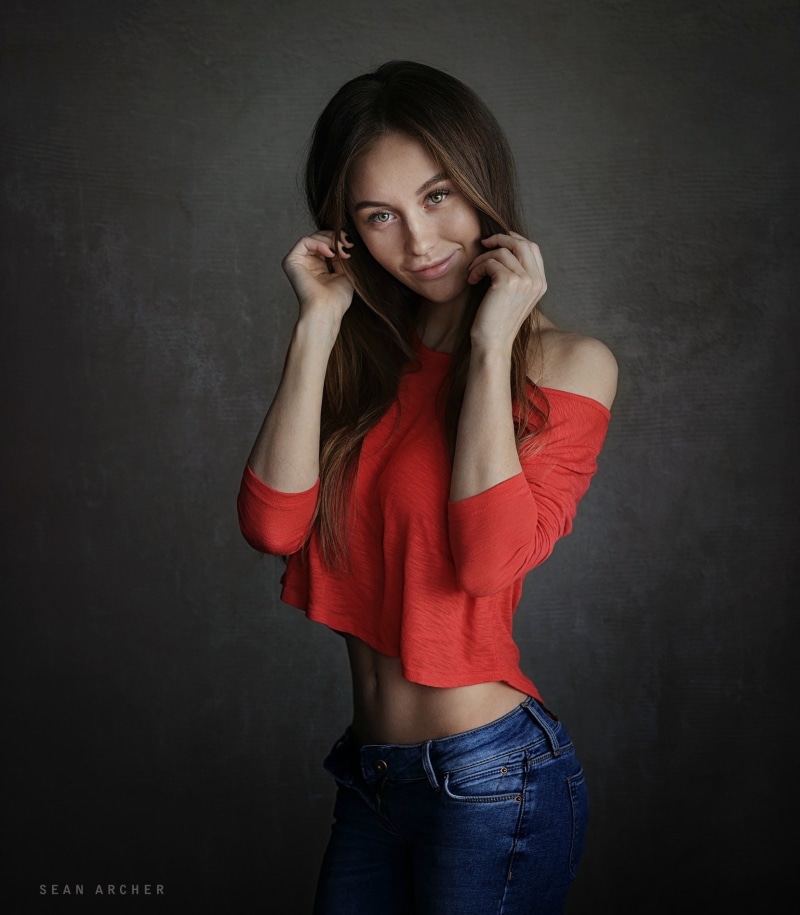 women, Olga Katysheva, holding hair, touching face, 720P, smiling, jeans, Sean Archer, red tops, simple background, model, 500px