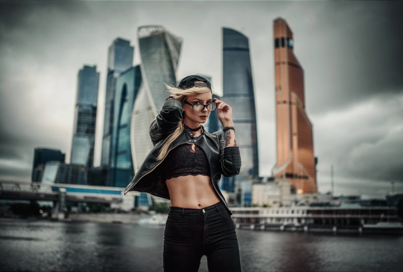 belly, urban, beautiful woman, 2K, focus on foreground, leather jackets, portrait, clothing, young women, hairstyle, architecture, model, black tops, one person