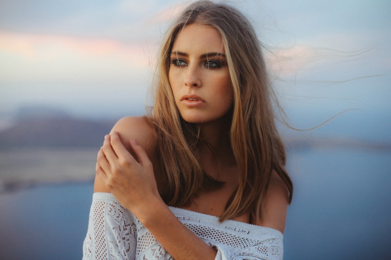 looking at camera, hands, teenager, contemplation, blonde, one person, adult, young adult, hairstyle, beautiful woman, depth of field, women outdoors, looking away