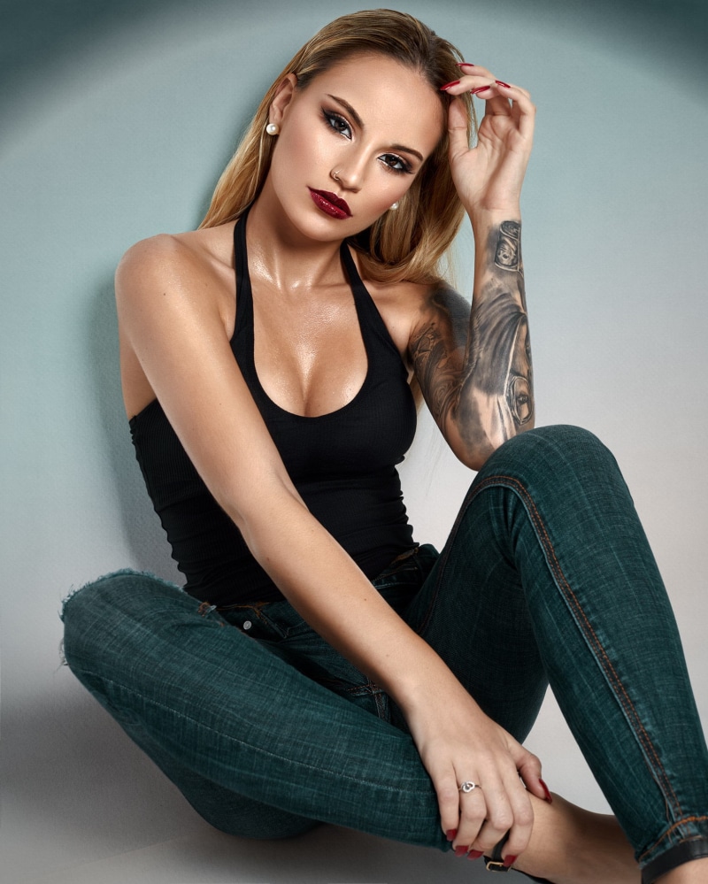 tattoo, looking at viewer, 1080P, pierced nose, sweat, eyeshadow, jeans, wall, women, cleavage, denim, tank top, beads, body oil, red nails, straight hair