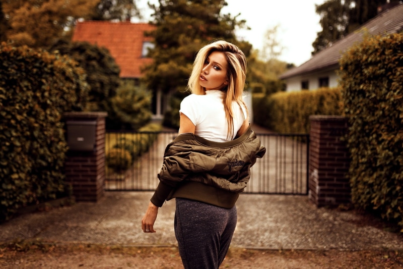 depth of field, architecture, women, outdoors, lifestyles, looking at viewer, three quarter length, sweater, one person, focus on foreground, fashion, young adult