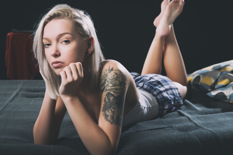 looking at viewer, blonde, inked girls, women, in bed, skirt, 1080P, model, tattoo, barefoot, legs up, face