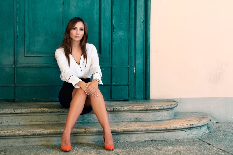 door, women outdoors, hairstyle, beautiful woman, Luigi Malanetto, beauty, sitting, skirt, fashion, real people, full length, outdoors, front view, looking at camera
