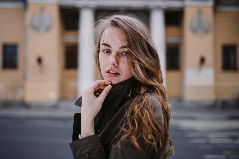 1080P, hairstyle, one person, looking at viewer, human hair, hair, building exterior, face, headshot, young women, architecture, focus on foreground, beautiful woman