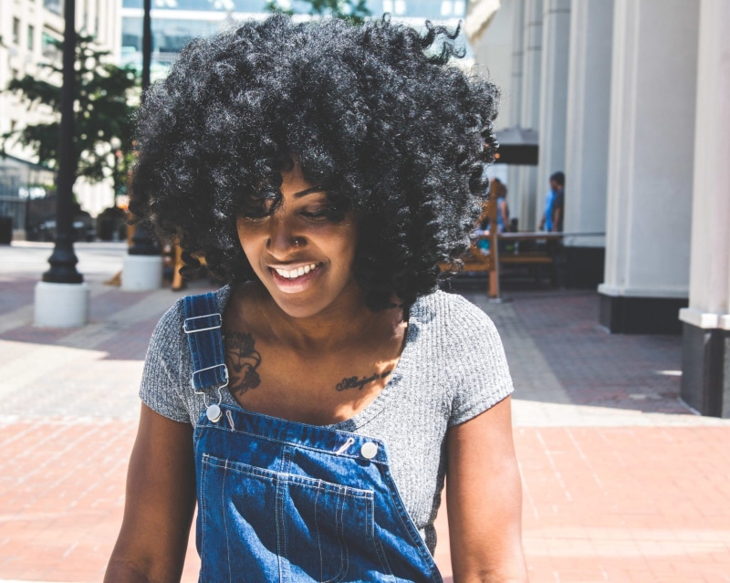 focus on foreground, people, woman, outdoors, curly, daylight, scoop, front view, tattoo, blue, smile, smiling, frizzy, women, adult, daytime, gray, pavement