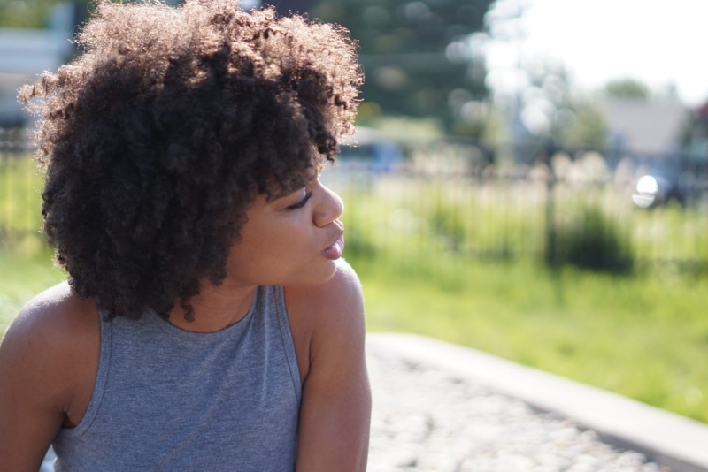 adult, focus on foreground, contemplation, person, headshot, daylight, smiling, afro, 720P, outdoors, day, gray, one person, girl, top, casual clothing