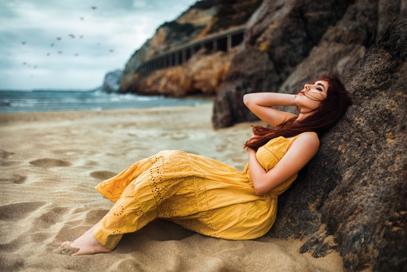 sitting, rocks, depth of field, outdoors, women, parted lips, side view, model, women on beach, sand, women outdoors, barefoot, yellow dress, brunette