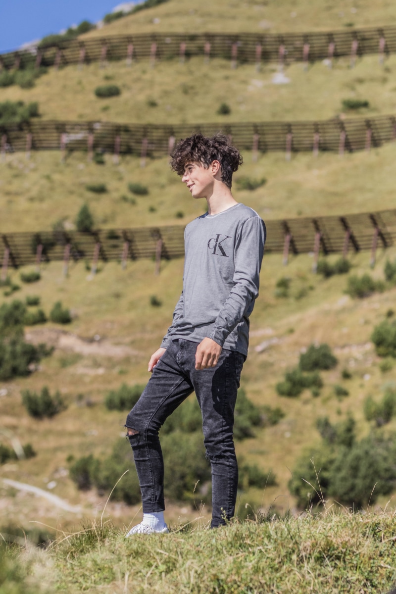 portrait, guy, stand, plant, hill, focus on foreground, senior photo, person, green, young men, grassfield, curly hair, casual clothing, standing, facing