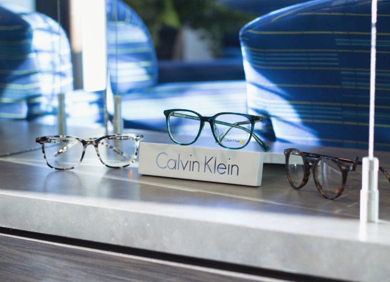 glass - material, outdoors, glasses, eyeglasses, western script, focus on foreground, day, glass, transparent, text, blue, no people, personal accessory