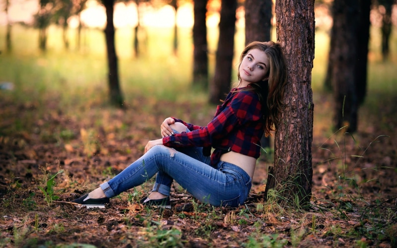 land, tree, portrait, plant, beautiful woman, forest, full length, day, shirt, autumn, tree trunk, model, sitting, casual clothing, trunk, hairstyle, torn jeans