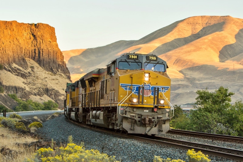 landscape, public transportation, mode of transportation, mountain, rail transportation, desert, train - vehicle, locomotive, cliff, transportation, shadow