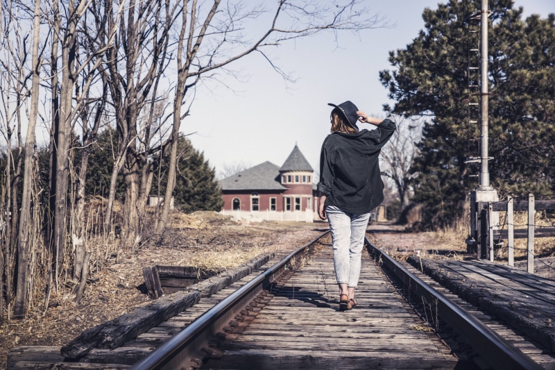 track, wearing, rear view, rail transportation, hat, day, train, casual clothing, walking on, bare tree, tracks, retro, nature, transportation, tree, one young woman only