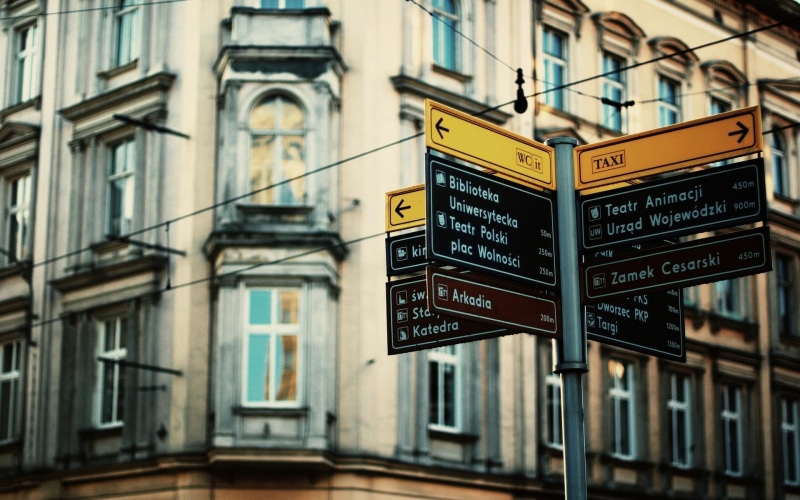 road sign, city, sign, Poland, script, text, wooden, street, non-western script, day, communication, no people, information, guidance, outdoors, built structure