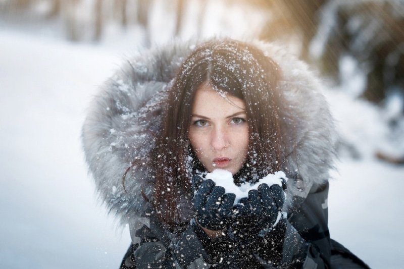 looking at viewer, snow, warm clothing, clothing, one person, hoods, brown hair, nature, brown eyes, winter coat, adult, fur, beauty, coat, outdoors, jacket