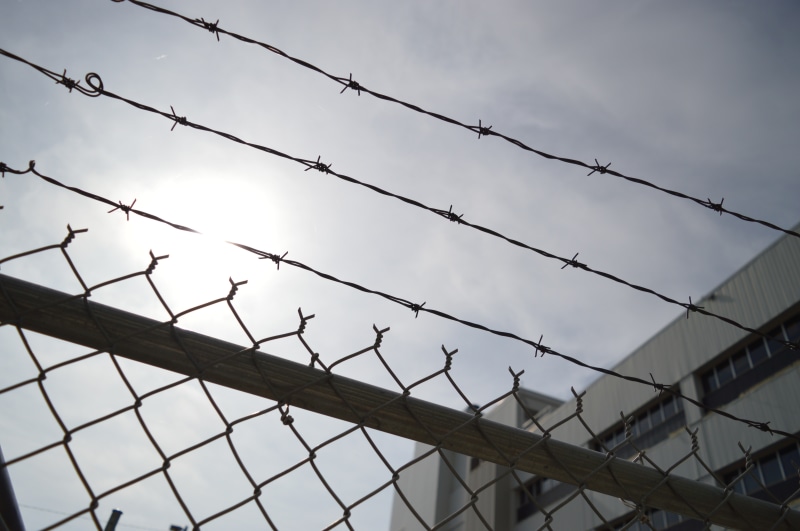 gray, enclose, fence, steel, jail, built structure, no people, cyclone, sign, cage, top, razor wire, 5K, wire, mesh, sharp, sky, barbwire, low angle view