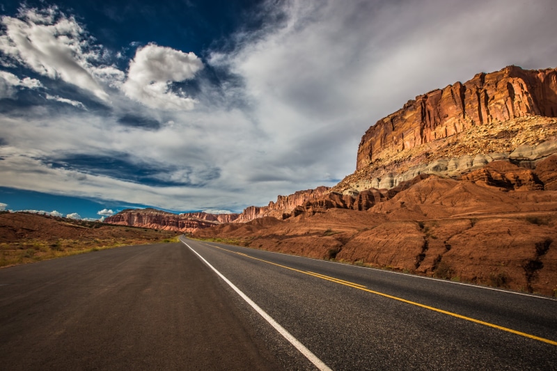 beauty in nature, scenics, blue, brown, diminishing perspective, travel, mountain, arid climate, near, roadway, southwest, famous, highway, sign, cloud - sky