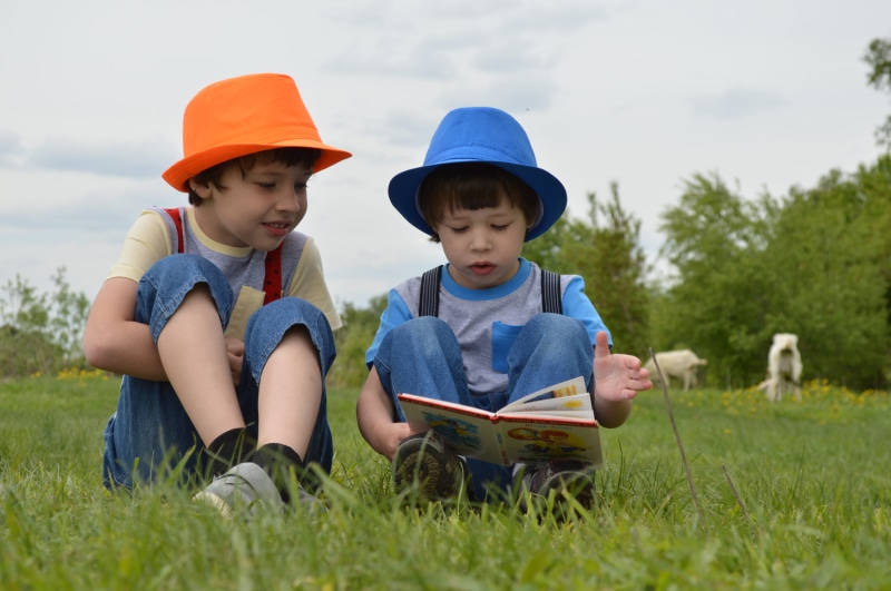 men, meadow, small child, sitting, front view, children model, grass, childhood, people, 5K, book, child, person, casual clothing, innocence, two people