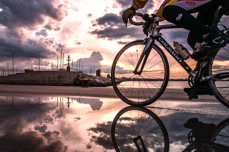 bicycle, velosipedist, building exterior, bike, water, orange color, sunset, sky, road, transportation, colnago, mode of transportation, spoke, land vehicle