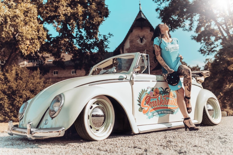 convertible, stationary, day, 1080P, pose, plant, vintage car, girl, motor vehicle, leisure activity, road, teal, retro styled, transportation, mode of transportation