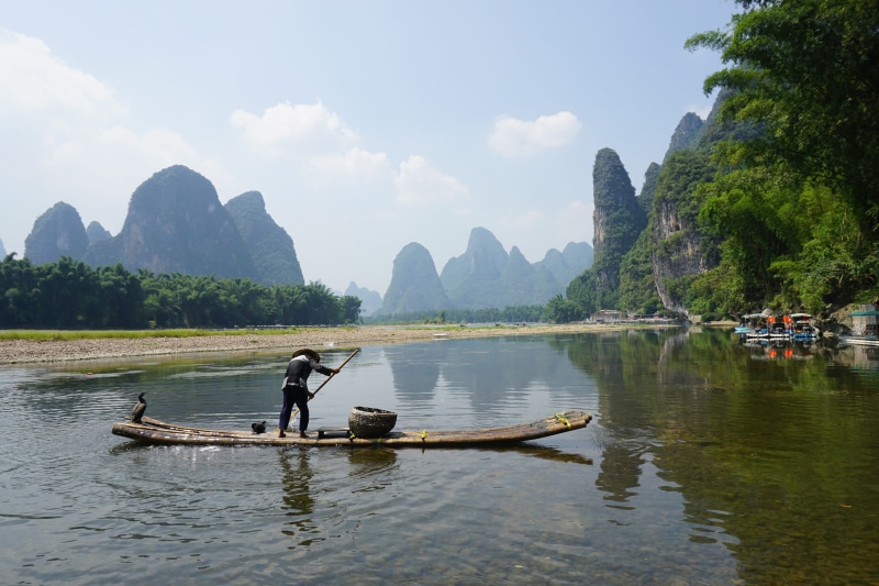 sky, xingping, day, mountain, river, mountain range, nature, men, fishman, waterfront, transportation, travel, non-urban scene, nautical vessel, outdoors