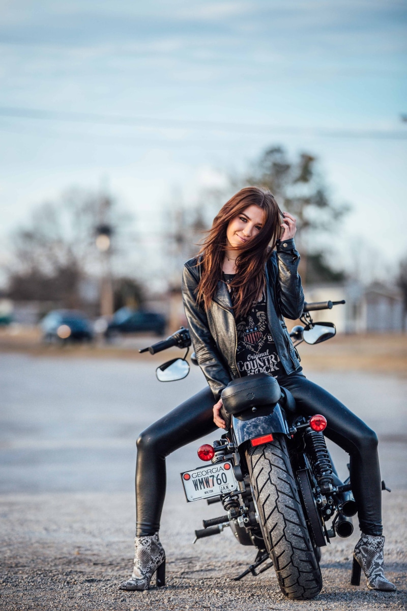 smiling, full length, leather jacket, fashion, one person, beautiful woman, biker woman, snake skin and leather, countryside riding, front view, sitting