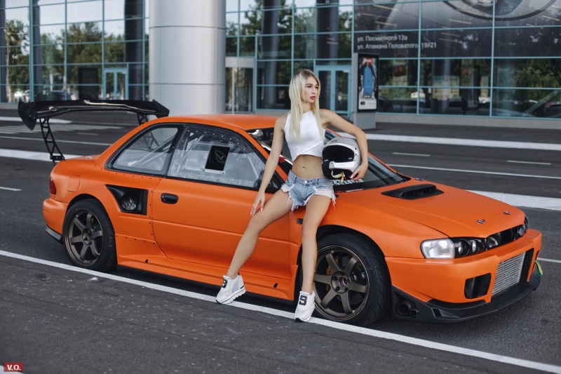 jean shorts, transportation, 1080P, belly, sneakers, car, looking away, motor vehicle, mode of transportation, building exterior, one person, built structure